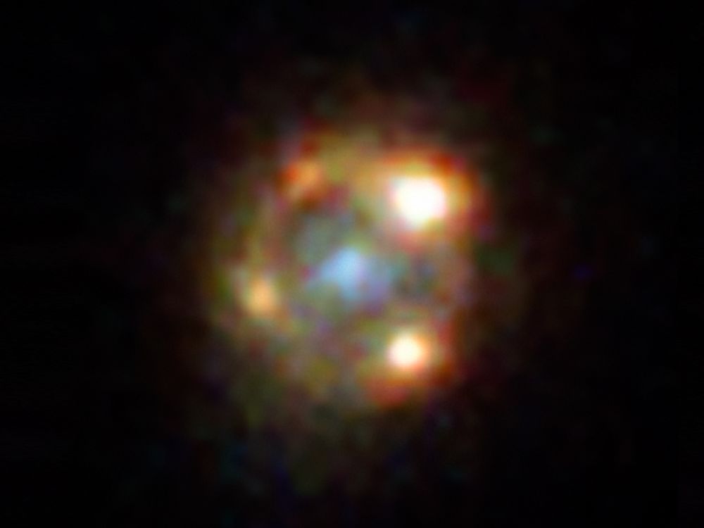 Like a lens, a galaxy (center, blue) passing in front of a supernova has split its light into four images (yellow/orange), and magnified its intensity by 52 times.